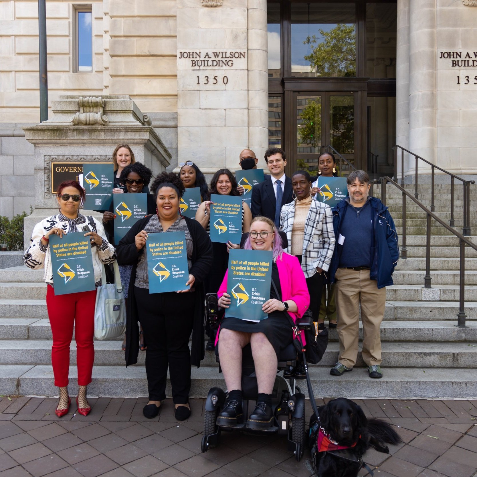 12 Group of members of D.C. Crisis Response Coalition holding dark green signs with the D.C. Crisis Response logo